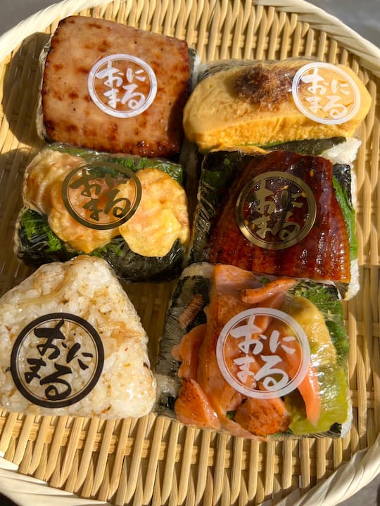 Close-up of colorful and aromatic onigiri in bamboo baskets at KYOTO ONIMARU, an onigiri (rice ball) shop in Kyoto